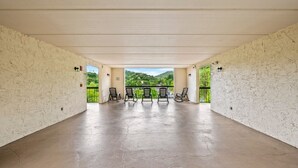 An open space with a concrete floor, a row of chairs, and a view of greenery through a glass door. - GC507•walk downtown •onsite heated pool (Gatlinburg)