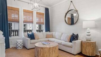 A living room with a white sofa, round coffee table, and a round mirror on the wall.