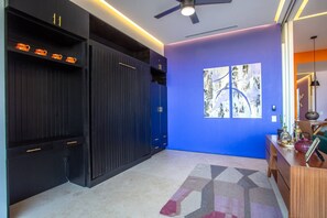 Un interior moderno con una pared azul de acento, un ventilador de techo y una alfombra de estampado geométrico.