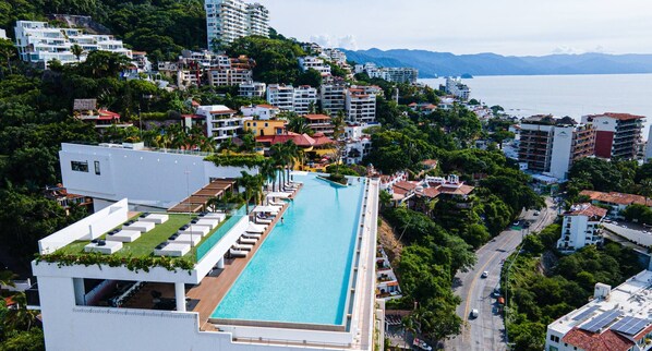 Un hotel con piscina larga, varias plantas y vistas al mar.