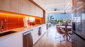 A modern kitchen with a built-in oven, a sink, and a dining area with a table and chairs. - Iconic Rooftop, Bar & Gym | Luxe 2 BR at Soho PV (Puerto Vallarta)