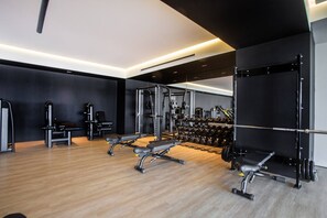 Ein modernes Fitnessstudio mit verschiedenen Trainingsgeräten, darunter Kraftgeräte, Bänke und Kurzhanteln.