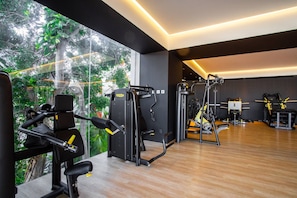 Et moderne fitnesscenter med forskellige træningsmaskiner, store vinduer og trægulv.