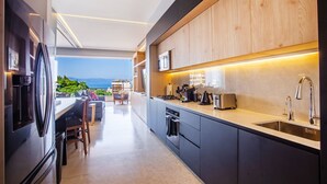 A modern kitchen with a view of the ocean, a dining area with a table and chairs, and a built-in oven.