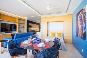 A modern living room with a sofa, dining table, chairs, and a TV. - Soho PV Oceanview Retreat w/ Heated Pool (Puerto Vallarta)