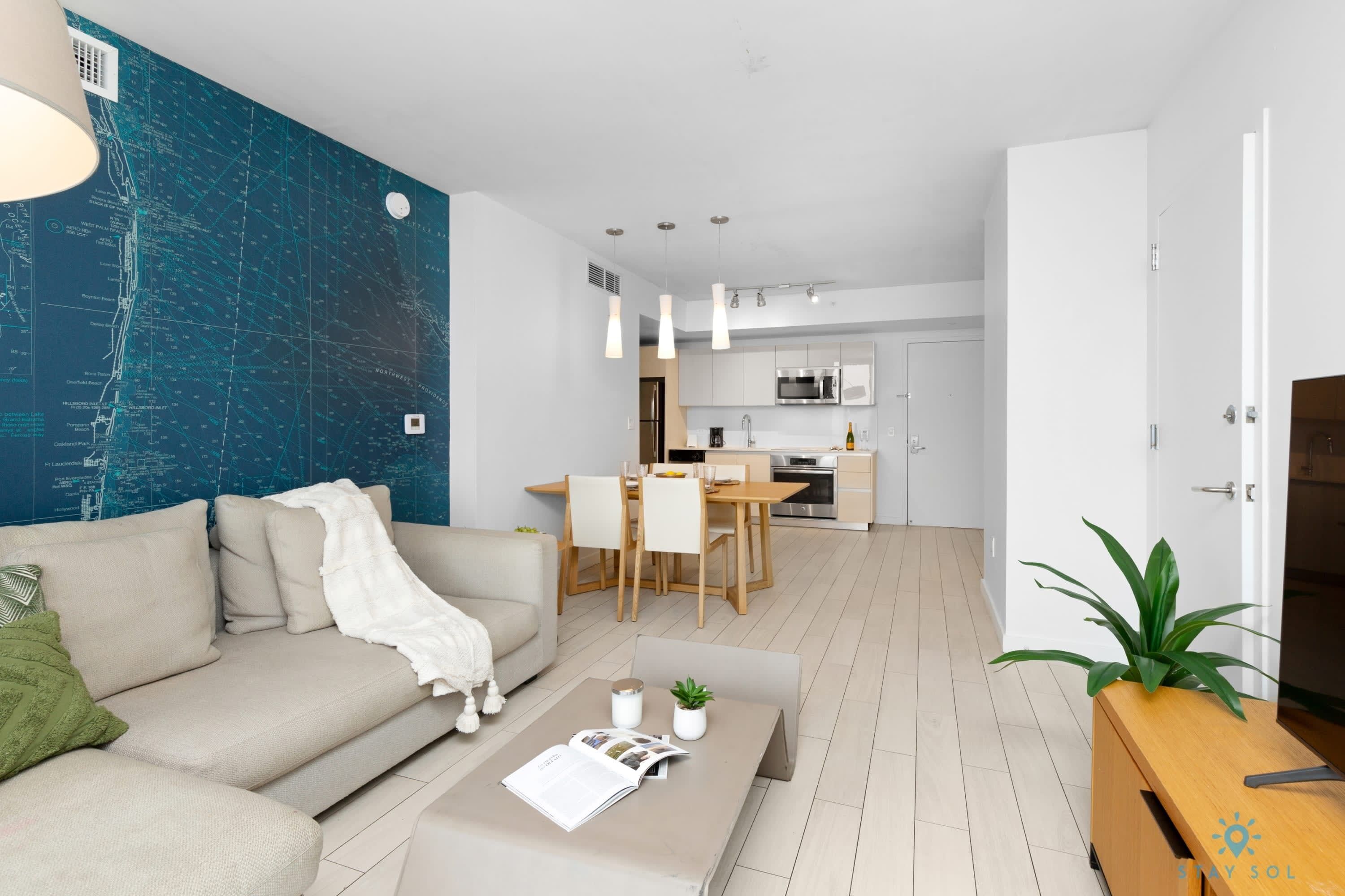 A modern living room with a sofa, coffee table, and a dining area with chairs and a table.