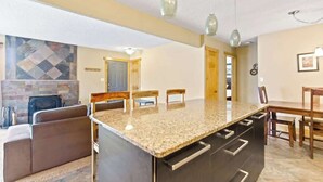 Une cuisine dotée d’un plan de travail en granit, de meubles en bois et d’un éclairage suspendu.