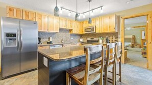 Une cuisine moderne avec des meubles en bois, des appareils en acier inoxydable et un îlot central doté de tabourets de bar.