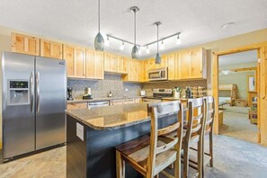 A modern kitchen with wooden cabinets, stainless steel appliances, and a central island with bar stools.
