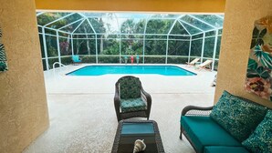 Ein Poolbereich mit Glasumrandung, Liegestühlen und einer Sitzecke.