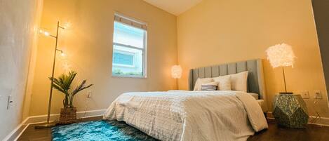 A bedroom with a bed, a ceiling fan, a window, and a blue rug.