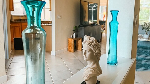Ein Zimmer mit einer weißen Kommode, auf der eine Büste und zwei Vasen stehen.