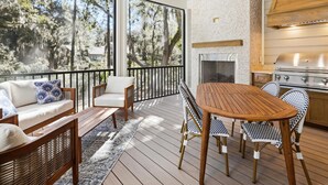 Un patio techado al aire libre con mesa y sillas de madera, un sofá y una chimenea.