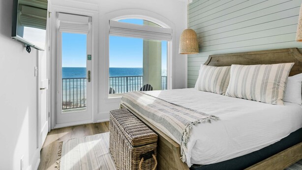 Ein Schlafzimmer mit großem Bett, Meerblick und einem Balkon.