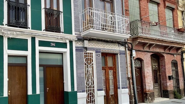 Una hilera de edificios tradicionales con balcones, puertas de madera y azulejos decorativos.
