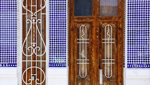 Puerta de madera con dos paneles de vidrio y detalles metálicos decorativos.
