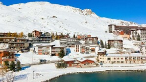 A snow-covered town with buildings, a lake, and mountains in the background.