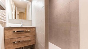 Une salle de bain avec un meuble-lavabo en bois, un miroir et des carreaux de couleur beige.