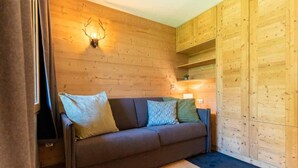 Une pièce chaleureuse avec un canapé marron, une petite table et des murs en bois.
