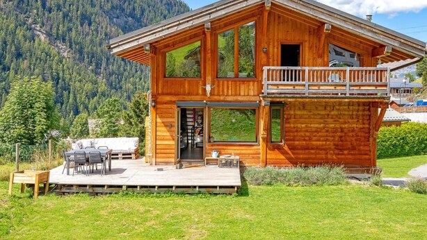 Une cabane en bois dotée d’un balcon, d’une terrasse et offrant une vue sur les montagnes.