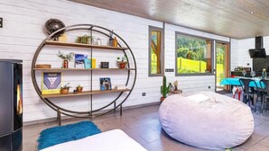 Un salon moderne doté d’une bibliothèque circulaire, d’un fauteuil en forme de poire et d’un coin repas offrant une vue sur la verdure.