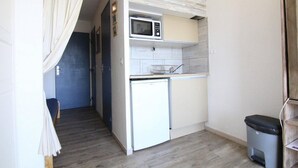 Una cucina compatta con un forno a microonde, un piccolo frigorifero e un lavandino.