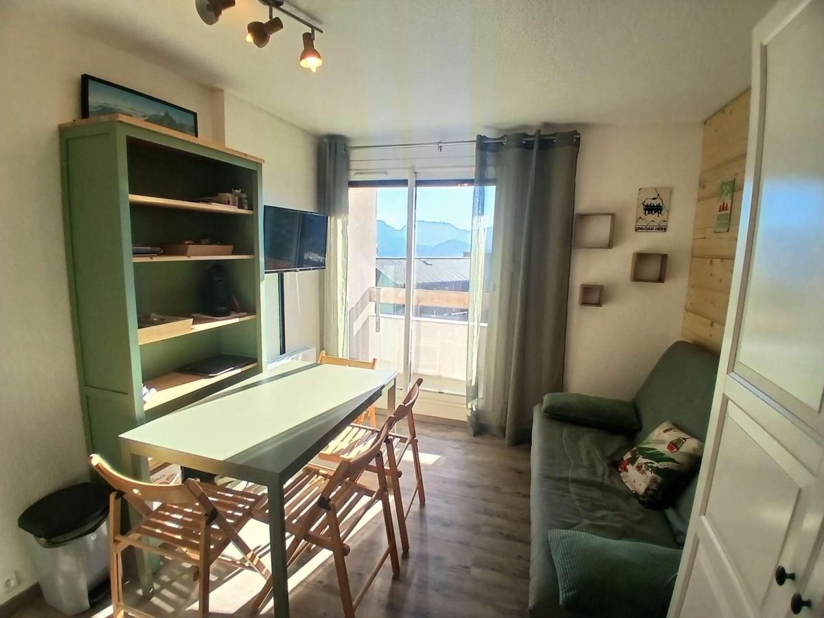 A compact living space with a dining table, chairs, a sofa, and a bookshelf.