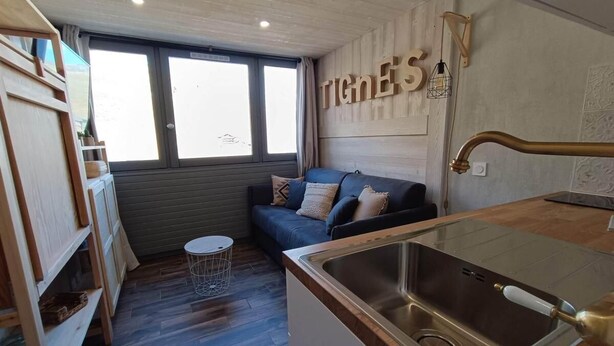A compact kitchen with a stainless steel sink, wooden shelves, a small round table, and a sofa with cushions. - 10m from resort center, 11st floor, view lake, tv, ski locker, 12m², Tignes (Tignes)