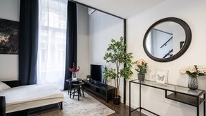A modern bedroom with a bed, a TV, a small table, a mirror, and a potted plant. - E41 Boutique Apartments by BQA (Budapest)