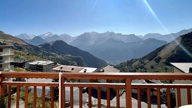 Une vue sur la montagne depuis un balcon doté d’une balustrade en bois.
