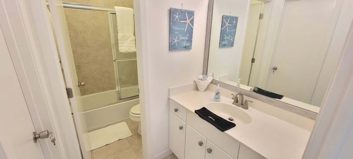 A bathroom with a shower, toilet, and a sink with a mirror.