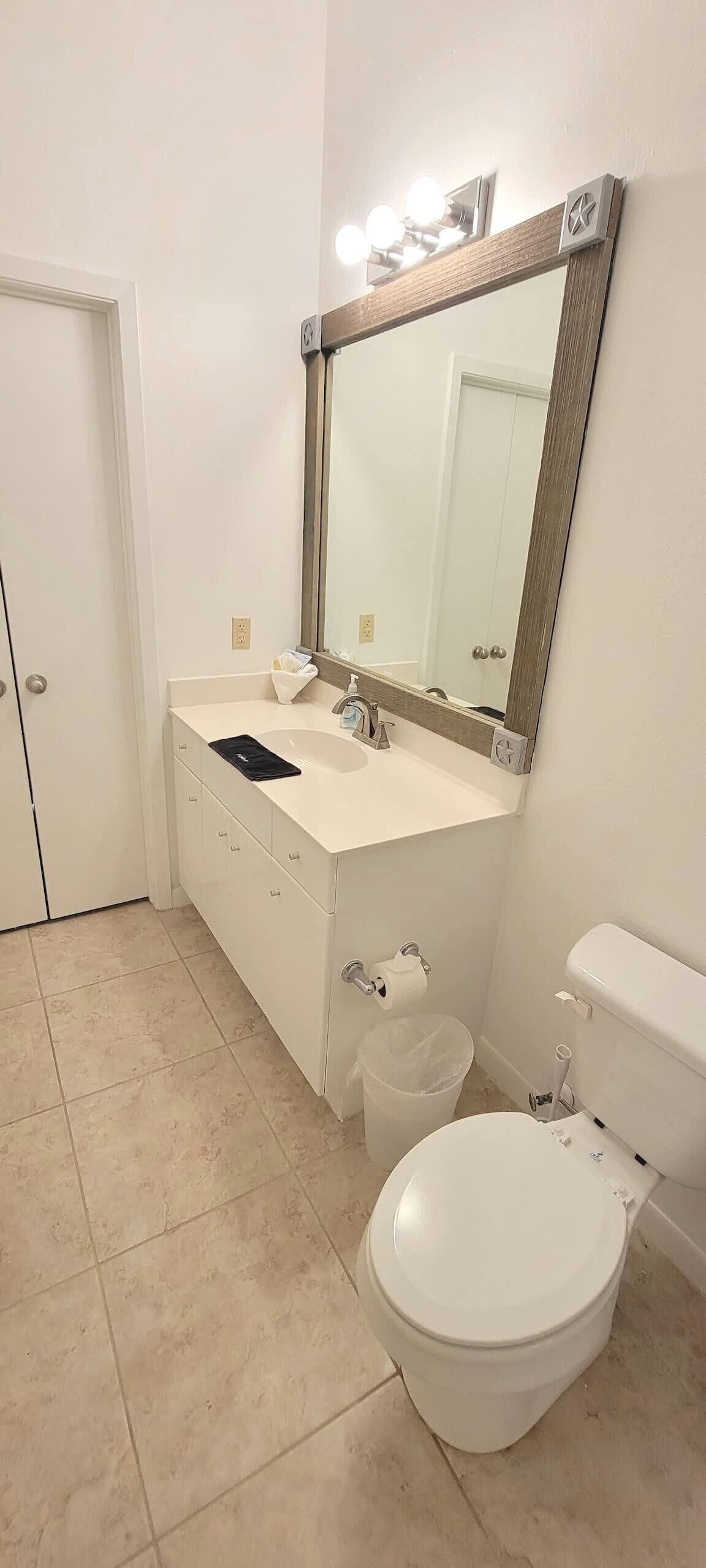A bathroom with a white sink, mirror, and toilet.