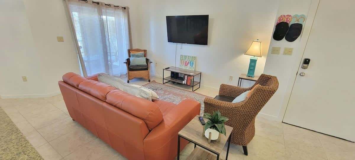 A living room with a sofa, armchair, coffee table, TV, and slippers on the wall.