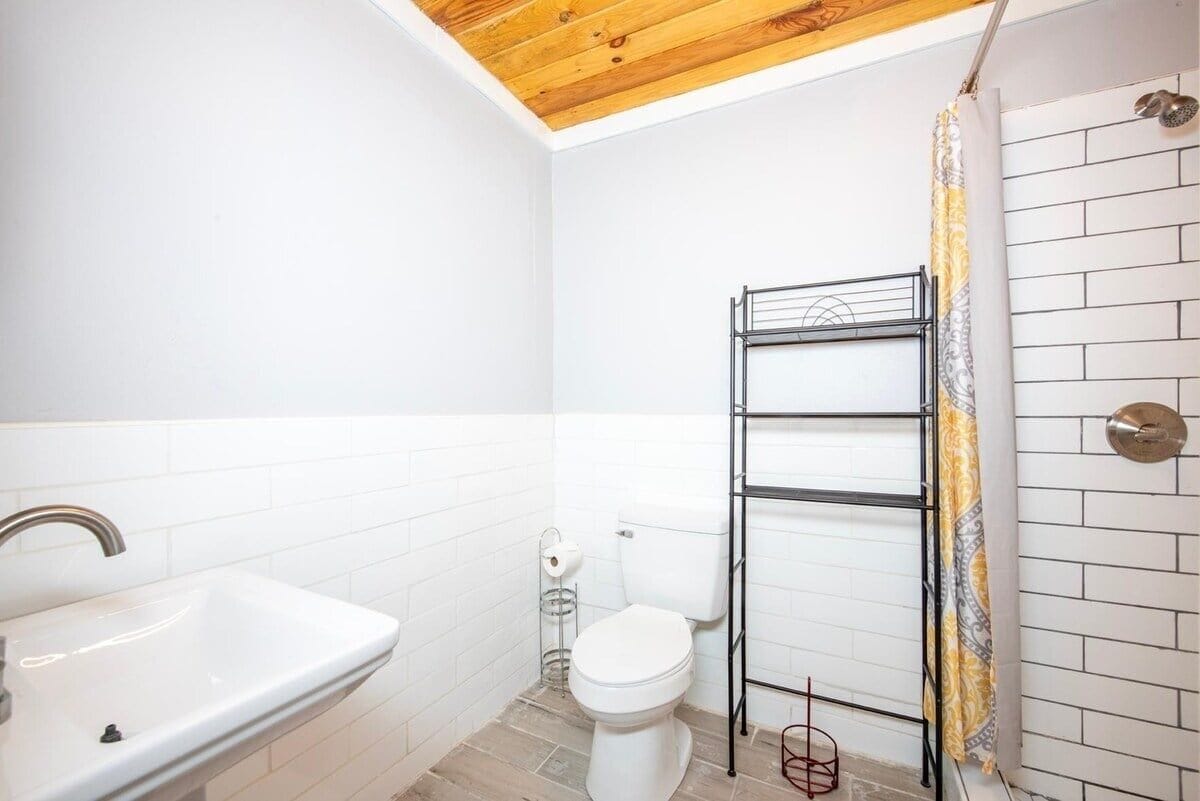 A bathroom with a white sink, toilet, and a metal shelf unit.