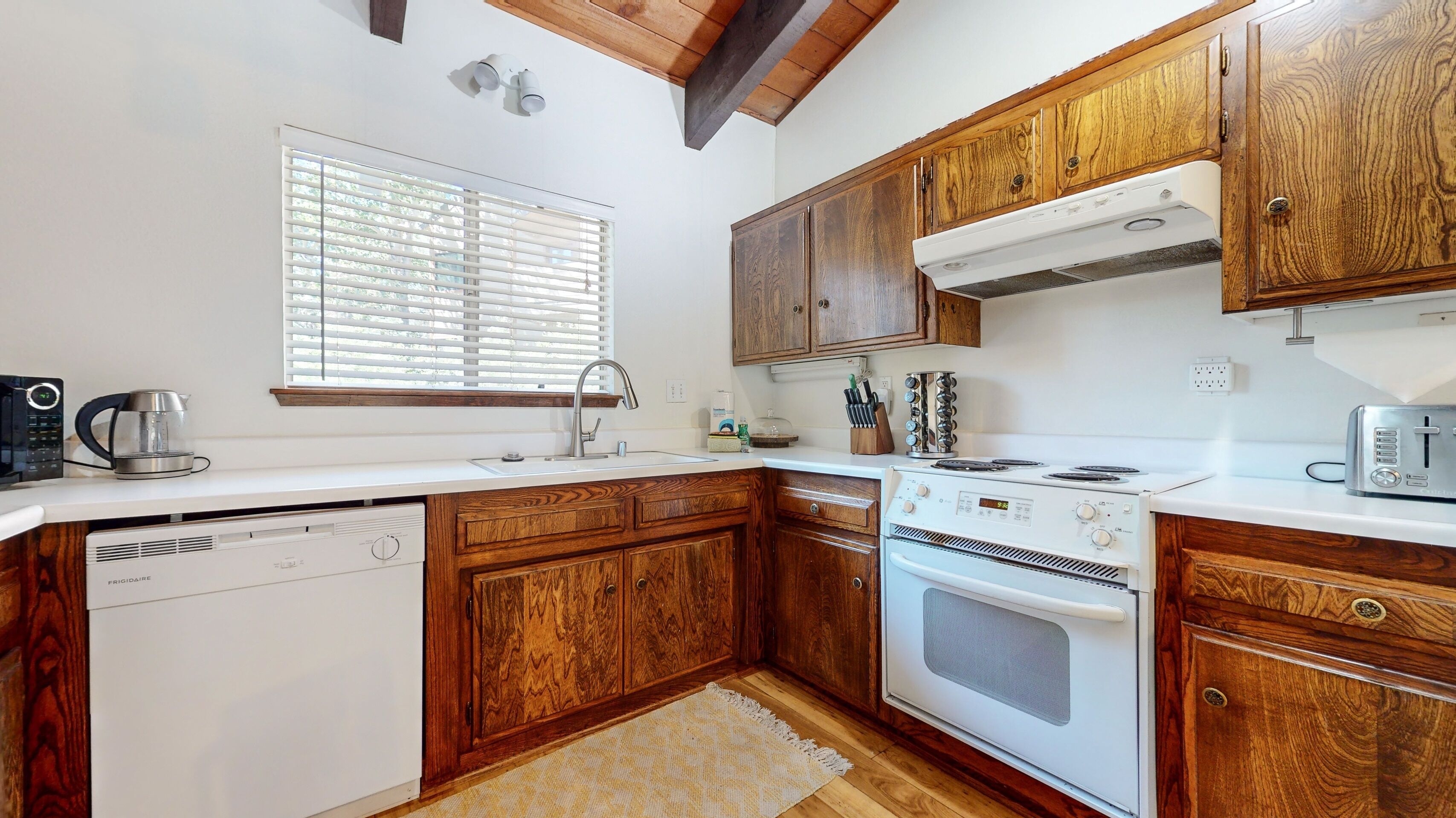 A kitchen with wooden cabinets, a white stove, and a dishwasher.