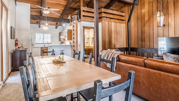 Un intérieur rustique avec une table à manger en bois, un canapé en cuir et un ventilateur de plafond.