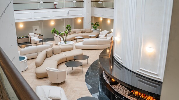 Amplia sala de estar moderna con disposición de asientos curva, chimenea y un entrepiso con más asientos.