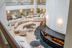 A spacious, modern lounge area with a curved seating arrangement, a fireplace, and a mezzanine level with additional seating.