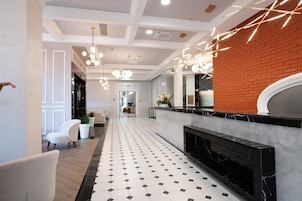 A modern hotel lobby with a black and white tiled floor, a fireplace, and a reception desk.