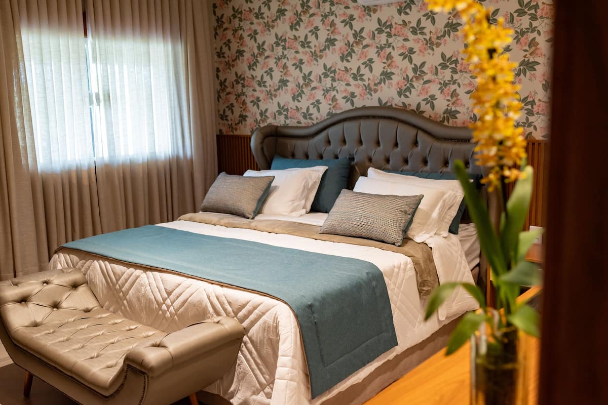 A bedroom with a bed, a bench, and a vase with flowers.