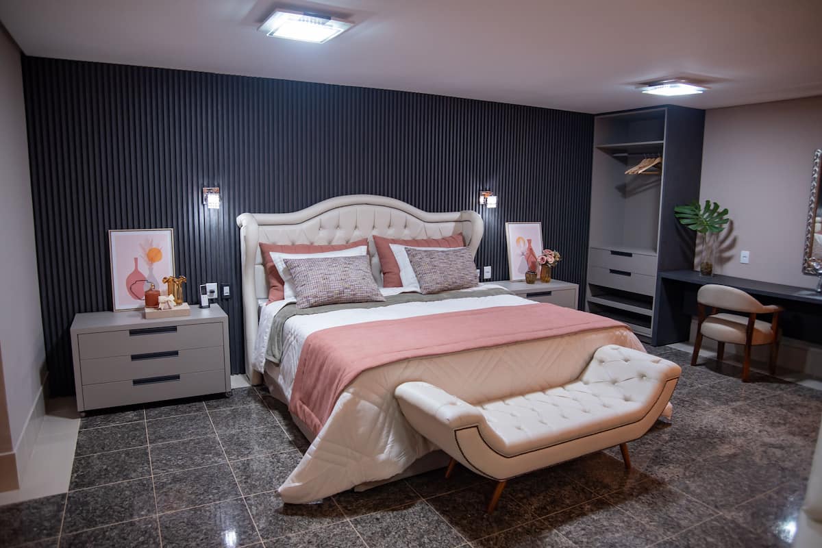 A modern bedroom with a large bed, bedside tables, a desk, and a chair.