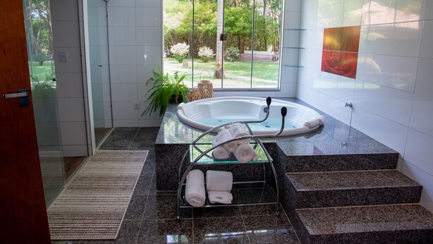 Un baño moderno con ducha envuelta en vidrio, una ba ñera y un estante de vidrio con toallas.