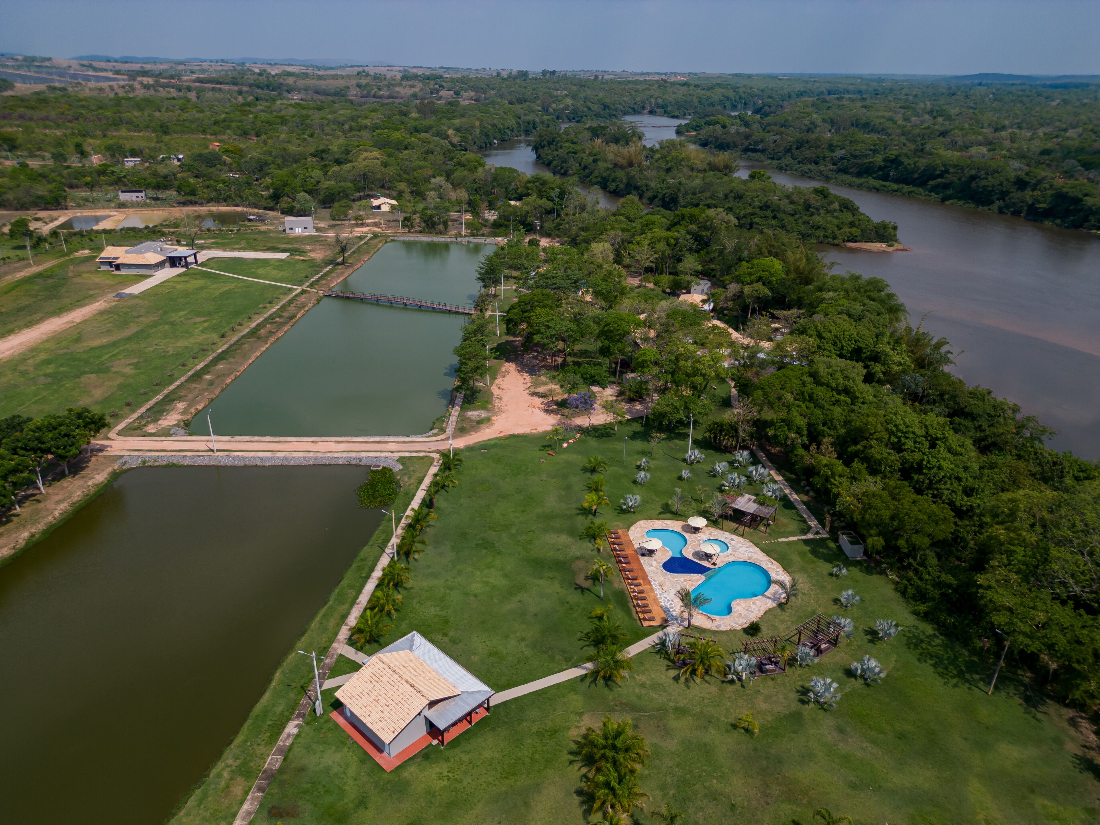 An aerial view of a resort with a swimming pool, a small building, and a large body of water.