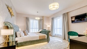 Un dormitorio moderno con una cama grande, un escritorio y un televisor en la pared.