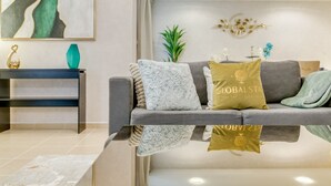 Una sala de estar moderna con un sofá gris, un jarrón verde azulado y un cojín dorado con el texto "GLOBALSTAR".