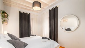 A bedroom with a bed, two pillows, a bedside table, a lamp, a mirror, and curtains. - Isidora's House by Corfuescapes (Corfu)