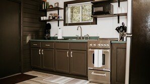 Una cucina con pensili marrone scuro, un forno in acciaio inossidabile, un microonde e una finestra sopra il lavello.