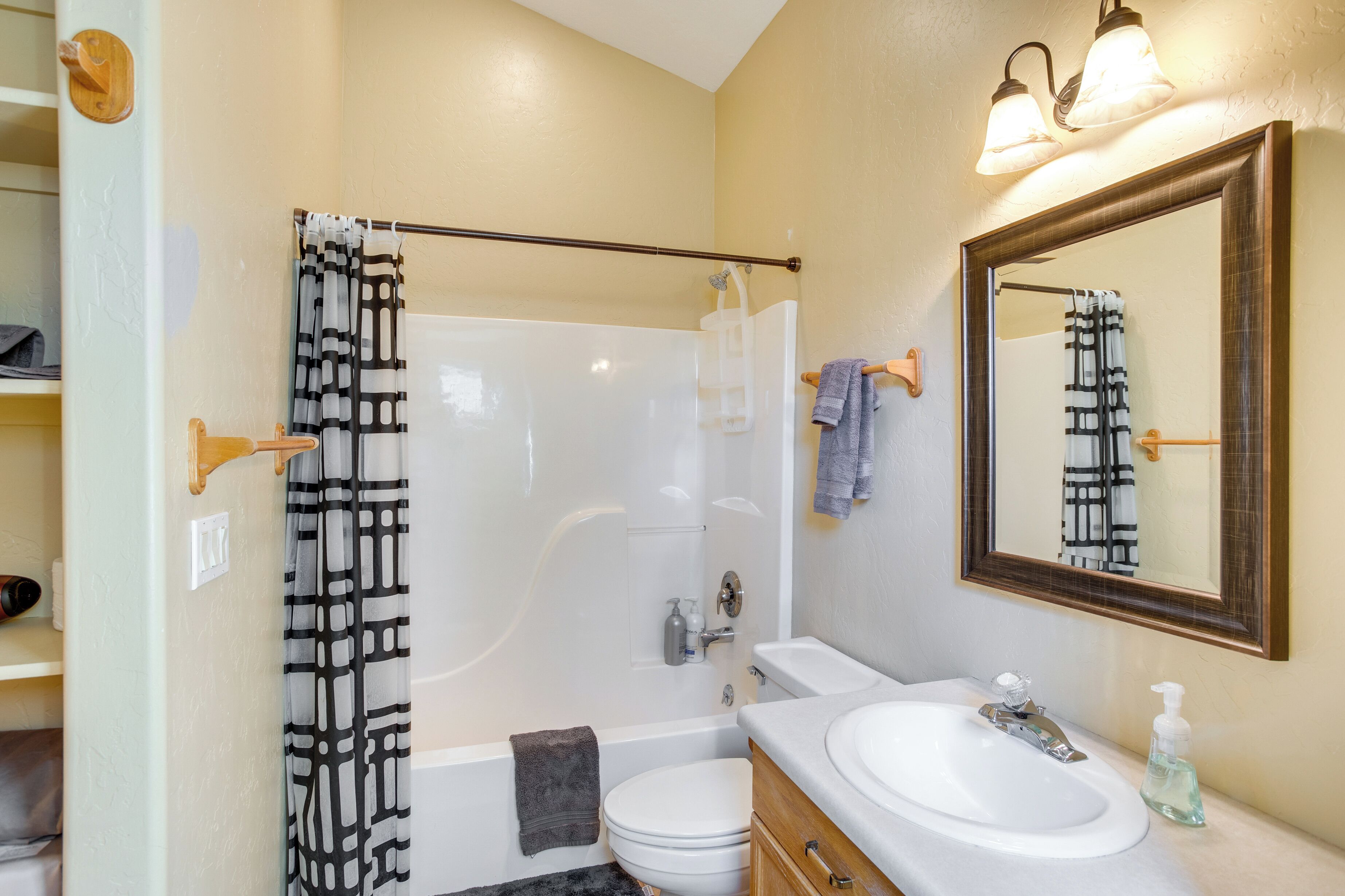 A bathroom with a bathtub, toilet, sink, and a mirror.