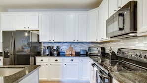 A modern kitchen with white cabinets, stainless steel appliances, and a tiled backsplash. - Walk to Boardwalk! Ocean City Coastal Gem w/ Deck (Ocean City)