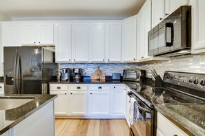Una cocina moderna con armarios blancos, electrodomésticos de acero inoxidable y un salpicadero de azulejos.
